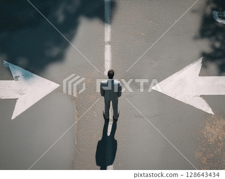 Businessman standing at a crossroads in life | Silhouette composition symbolizing choice and uncertainty Businessman standing at a crossroads in life | Silhouette composition symbolizing choice and uncertainty 128643434