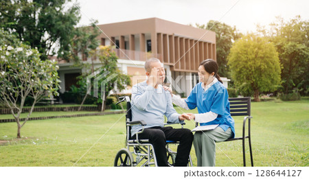 Asian careful caregiver or nurse and the happy patient in a wheelchair are walking in the garden. to help and encourage and rest your mind with green nature. Use a stethoscope to listen Asian careful caregiver or nurse and the happy patient in a wheelchair are walking in the garden. to help and encourage and rest your mind with green nature. Use a stethoscope to listen 128644127