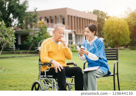 Asian young caregiver nurse support senior older male walking outdoors. Specialis doctor help and take care of elderly mature. Nursing home hospital garden Asian young caregiver nurse support senior older male walking outdoors. Specialis doctor help and take care of elderly mature. Nursing home hospital garden 128644130
