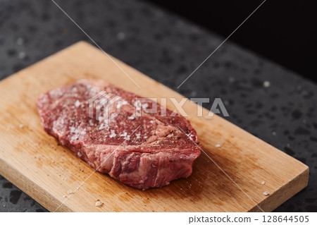 Raw ribeye steak spiced and ready to cook on oak board 128644505