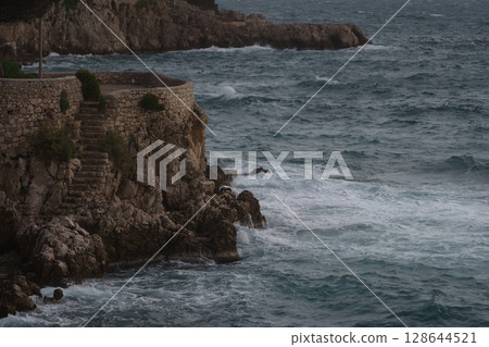 Sea waves crashing against the rocks of mediterranean shore Sea waves crashing against the rocks of mediterranean shore 128644521
