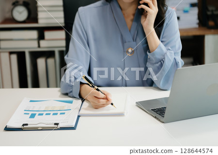 businesswoman hand writing on the notepad with new modern computer strategy diagram as concept 128644574