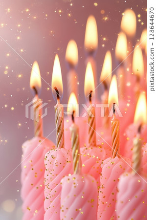 A close-up image of festive pink birthday candles with flickering flames and a dreamy, sparkly background. 128644670