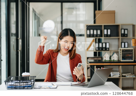 Young beautiful woman using laptop and tablet while sitting at her working place. Concentrated at work. Young beautiful woman using laptop and tablet while sitting at her working place. Concentrated at work. 128644768