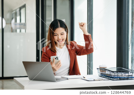 Young beautiful woman using laptop and tablet while sitting at her working place. Concentrated at work. 128644769