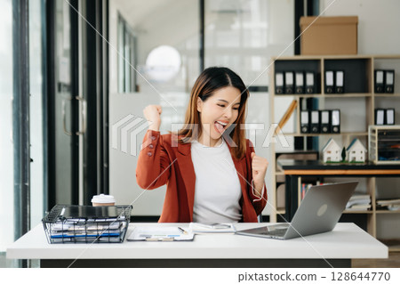 Young beautiful woman using laptop and tablet while sitting at her working place. Concentrated at work. Young beautiful woman using laptop and tablet while sitting at her working place. Concentrated at work. 128644770