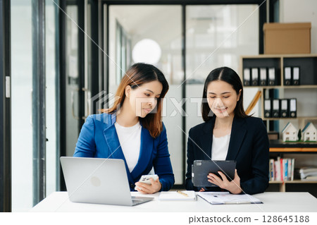 Businesswoman leading team meeting and using tablet and laptop computer with financial in office Businesswoman leading team meeting and using tablet and laptop computer with financial in office 128645188