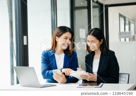 Businesswoman leading team meeting and using tablet and laptop computer with financial in office Businesswoman leading team meeting and using tablet and laptop computer with financial in office 128645190