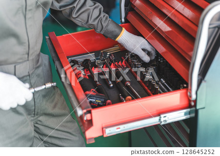 Middle-aged Asian man, mechanic, auto mechanic working at a repair shop Middle-aged Asian man, mechanic, auto mechanic working at a repair shop 128645252