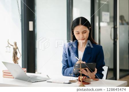 justice and law concept. asian woman lawyer working and judge in a courtroom the gavel, working with tablet and laptop justice and law concept. asian woman lawyer working and judge in a courtroom the gavel, working with tablet and laptop 128645474