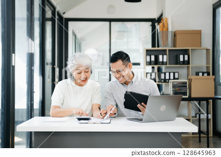 Two business workers talking on tablet and using laptop 128645963