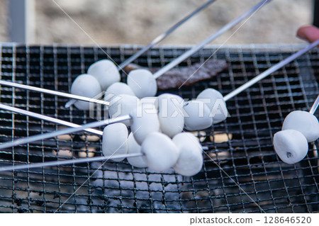 Roasting marshmallows at an outdoor barbecue 128646520