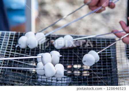 Roasting marshmallows at an outdoor barbecue 128646523