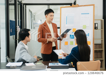 Mid age Asian business woman ceo executive manager showing to colleagues team income revenue data figures planning on big screen in modern office Mid age Asian business woman ceo executive manager showing to colleagues team income revenue data figures planning on big screen in modern office 128646676
