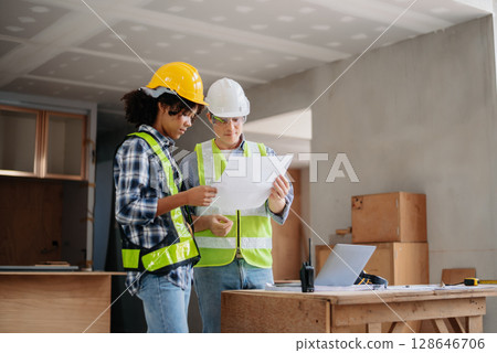 Engineers are discussing data working and laptop or tablet with architectural project at new construction site on big project. Engineers are discussing data working and laptop or tablet with architectural project at new construction site on big project. 128646706