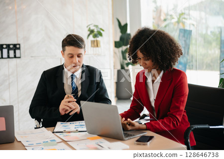 Two business workers talking on the smartphone and using laptop at the office. Two business workers talking on the smartphone and using laptop at the office. 128646738