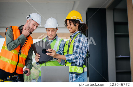 Architect caucasian man working with colleagues mixed race in the construction site. Architecture engineering on big project. Building in construction interior. 128646772