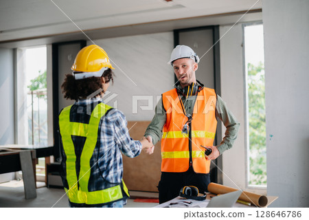 Construction team shake hands greeting start new project plan behind yellow helmet in office center to consults about their building project. Construction team shake hands greeting start new project plan behind yellow helmet in office center to consults about their building project. 128646786