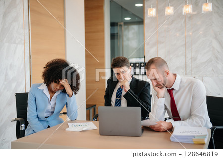 Team thinking of problem solution at office meeting, sad diverse business people group shocked by bad news, upset colleagues Team thinking of problem solution at office meeting, sad diverse business people group shocked by bad news, upset colleagues 128646819