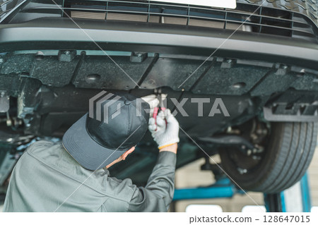 一名男性汽車修理工，在電梯上的車輛下進行維護、檢查和工作 128647015
