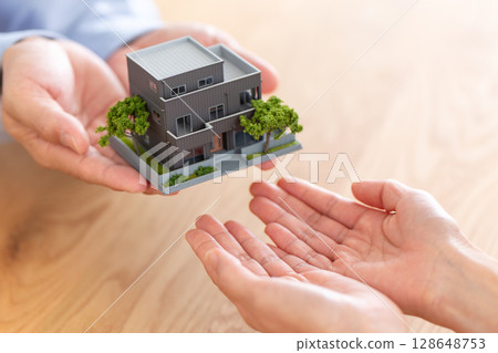 Hands of a middle-aged couple handing over a house 128648753