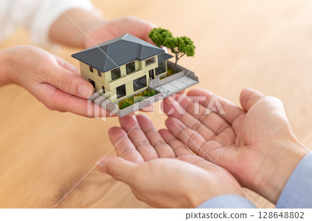 Hands of a middle-aged couple handing over a house 128648802