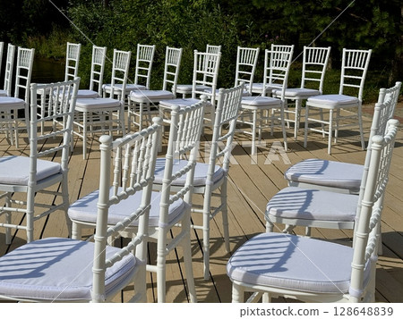 White chairs for the guests of the wedding ceremony are on the site. High quality photo 128648839