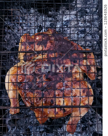Tobacco chicken is grilled on a charcoal grill in the backyard 128648926
