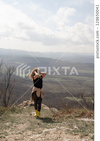 Hiking Woman Nature: Girl poses atop mountain overlook on cloudy day to capture scenic view. 128650041