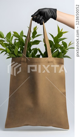 hand holding paper bag with green plant leaves hand holding paper bag with green plant leaves 128650052