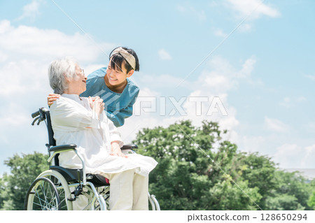 A granddaughter comes for a walk to visit her grandmother who is in a wheelchair 128650294