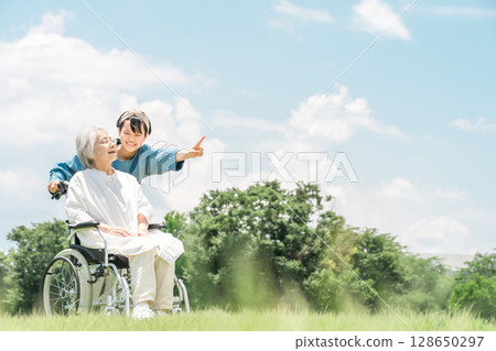 A granddaughter comes for a walk to visit her grandmother who is in a wheelchair 128650297