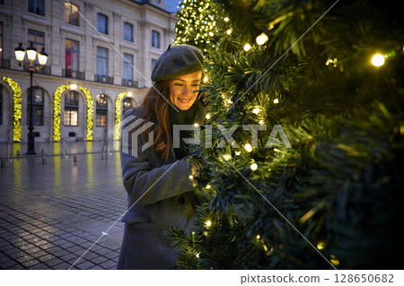Woman enjoying Christmas decorations on festive street 128650682