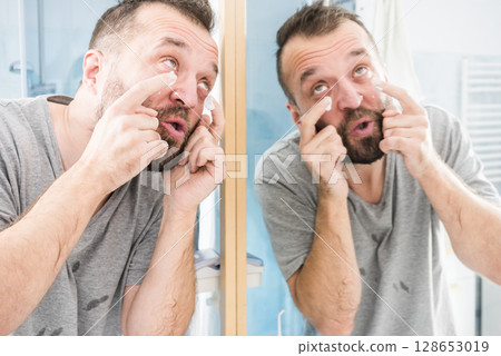 Man applying moisturizer cream in bathroom Man applying moisturizer cream in bathroom 128653019