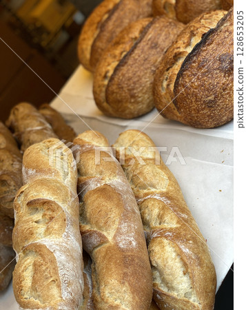 Freshly baked baguettes and sourdough loaves on display in a bakery shop setting 128653205