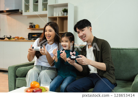Funing parents with daughter sitting on couch. Funing parents with daughter sitting on couch. 128653414