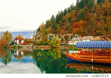 Autumn landscape with lake Bled, tradition wooden Pletna boats and old villa in Slovenia Autumn landscape with lake Bled, tradition wooden Pletna boats and old villa in Slovenia 128653514