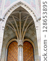 Mysterious Gothic arch and antique wooden door with ornate stone details, medieval architecture style. 128653895