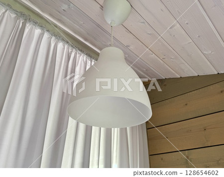 a white plastic ceiling lamp hangs on the ceiling. High quality photo a white plastic ceiling lamp hangs on the ceiling. High quality photo 128654602