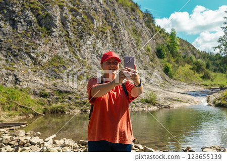 Young Female Hiker Taking a Selfie While Resting by a Mountain Stream 128655139