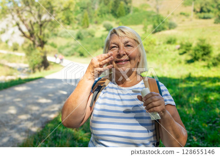 Senior Woman Enjoying a Refreshing Moment on a Nature Trail 128655146
