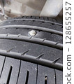 screw puncturing car tire. macro closeup. 128655257