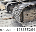 Metal excavator track background. Construction site ground. Heavy machinery equipment. 128655264