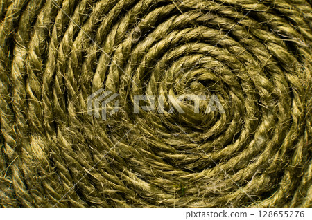 Natural green jute twine close-up. Detailed texture of a roll of coarse thread. Rustic cord background for packaging or crafts. Eco-friendly material for handmade and eco-friendly creativity Natural green jute twine close-up. Detailed texture of a roll of coarse thread. Rustic cord background for packaging or crafts. Eco-friendly material for handmade and eco-friendly creativity 128655276