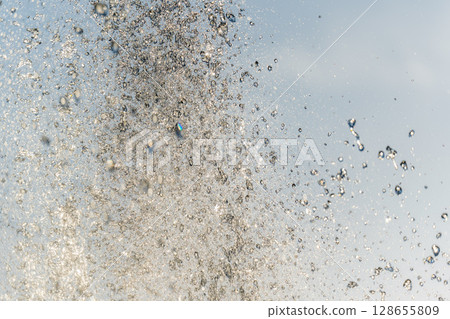 Splashes and jets of water against light background. Splashes and jets of water against light background. 128655809