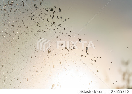 Splashes and jets of water against light background. Splashes and jets of water against light background. 128655810