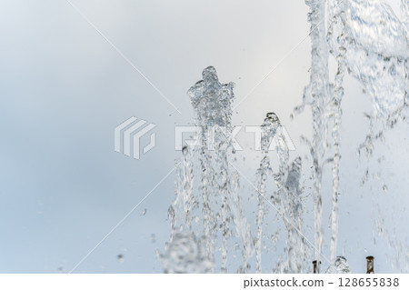 Splashes and jets of water against light background. Splashes and jets of water against light background. 128655838