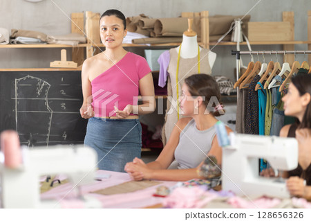 Female dressmaker explaining pattern modeling by chalkboard during course for beginners 128656326