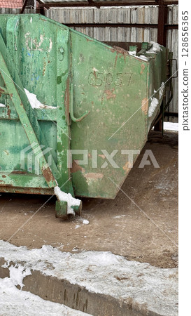 An old green metal container filled with garbage and waste products from residents of an apartment building in the courtyard. Waste management in an urban environment An old green metal container filled with garbage and waste products from residents of an apartment building in the courtyard. Waste management in an urban environment 128656365