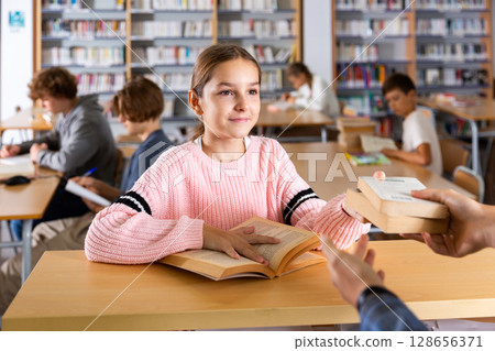 Girl giving books to librarian 128656371